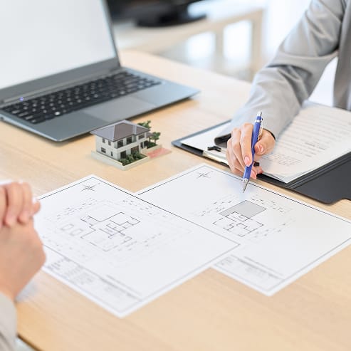 Two professionals at a table reviewing blueprints and a laptop, collaborating on a construction project for TOFCON in Ottawa.