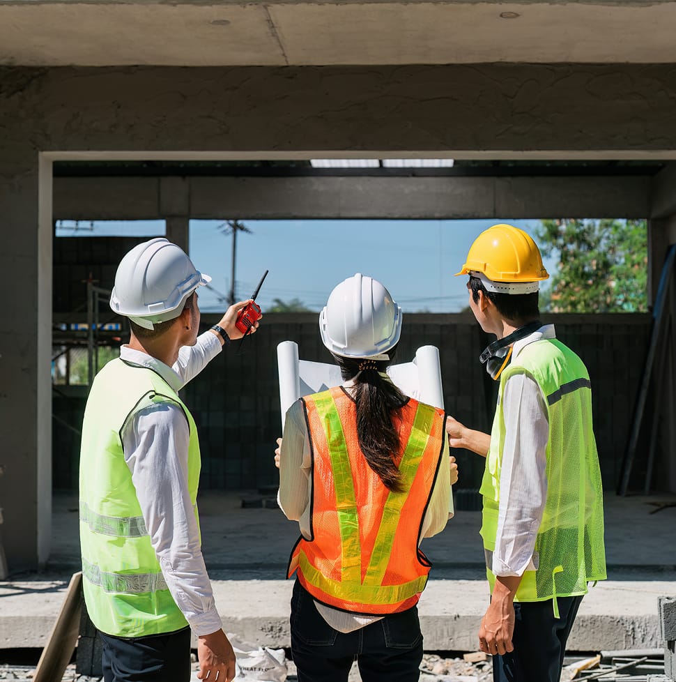 Three construction workers in hard hats and safety vests stand in front of a building, representing TOFCON careers in Ottawa.