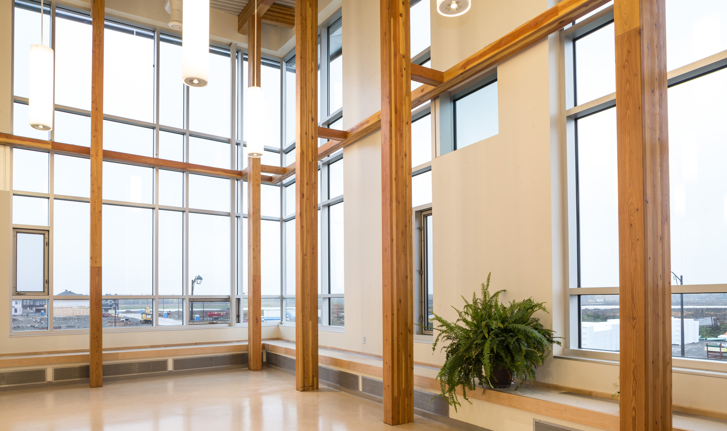 A spacious room featuring numerous windows and wooden beams, designed for Notre-Place Catholic Elementary School by TOFCON.