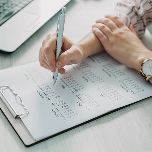 A close-up of a hand writing in a planner, representing project planning for TOFCON, an Ottawa-based construction firm.