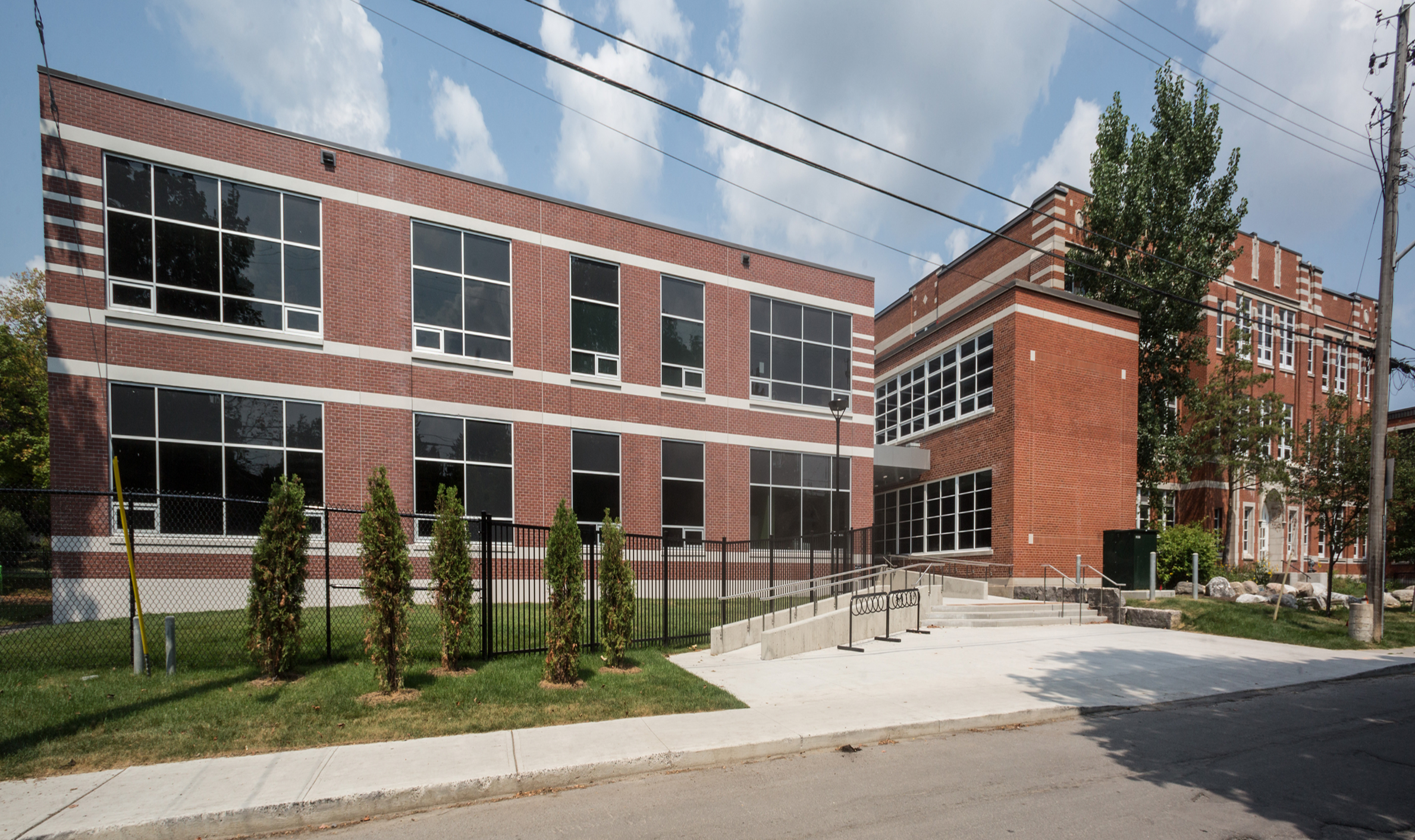 Large brick building with windows and a fence, showcasing TOFCON's construction work at Elmdale Public School in Ottawa.