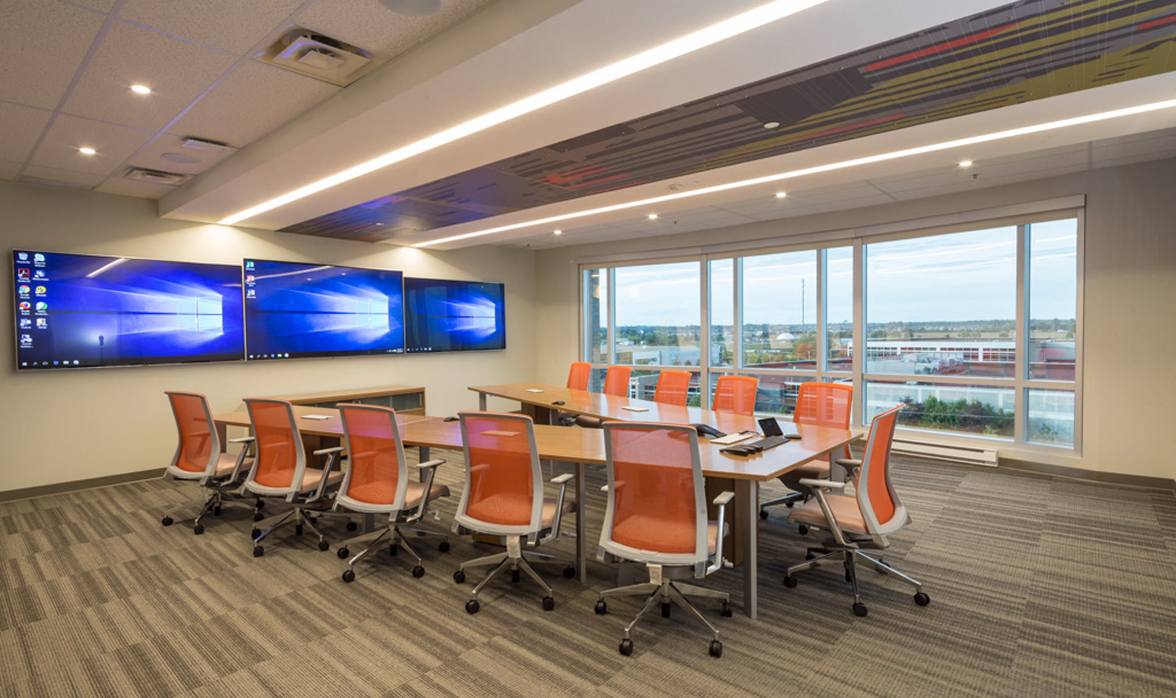 A conference room with orange chairs and a large screen, showcasing TOFCON's construction achievements for Kinaxis in Ottawa.
