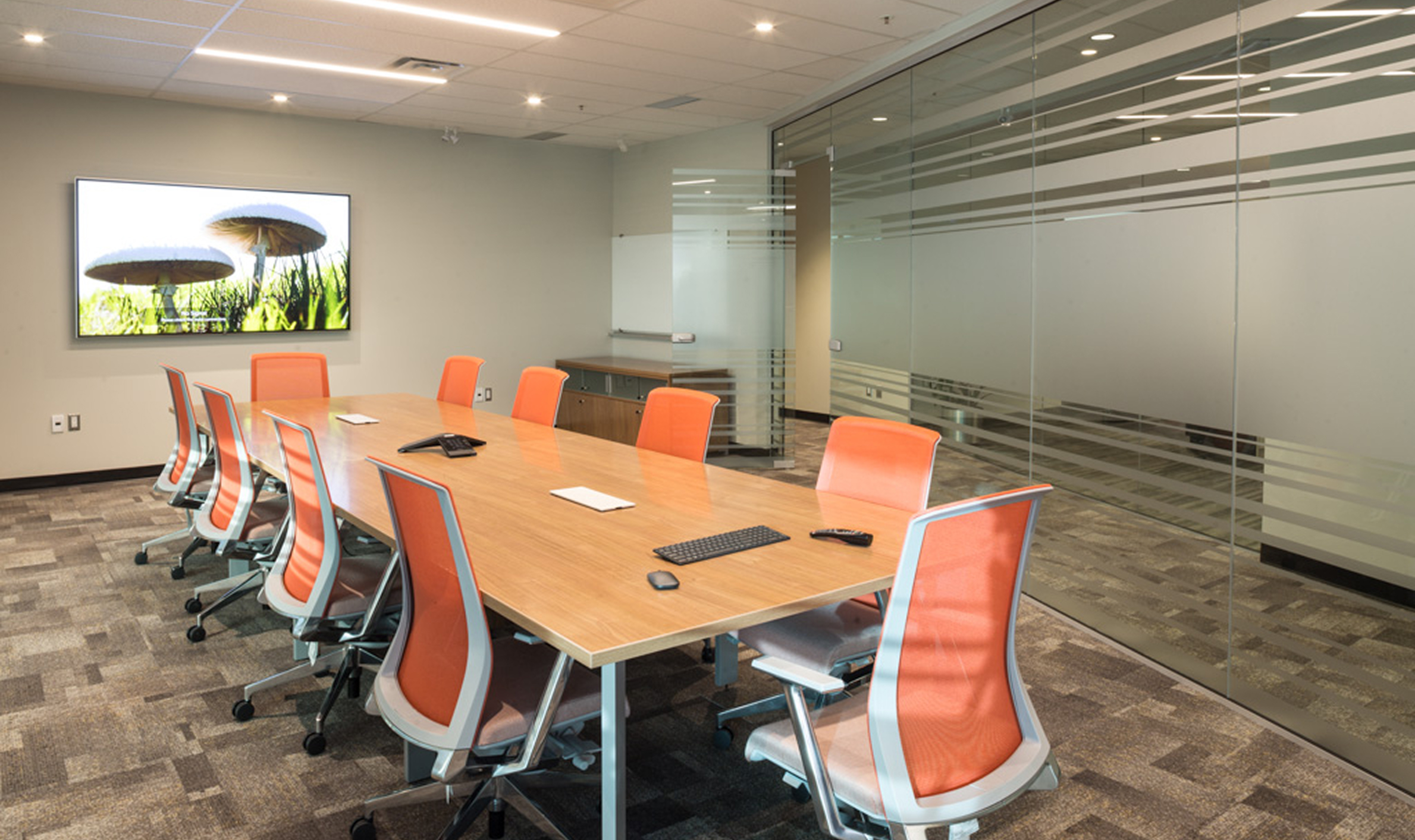 Conference room featuring orange chairs and a large glass wall, showcasing TOFCON's construction work for Kinaxis.